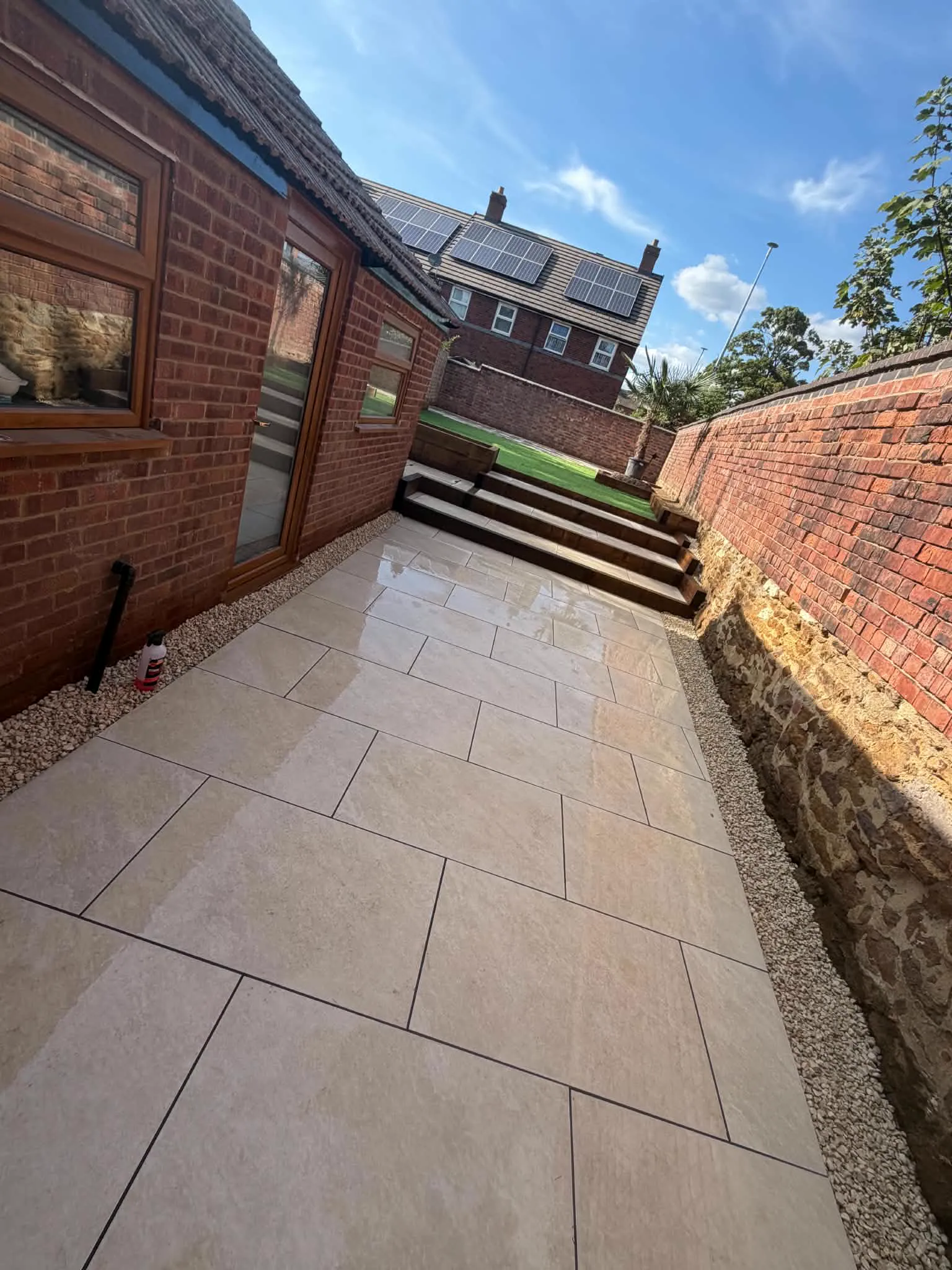 The same garden after porcelain-style paving, steps and a new lawn